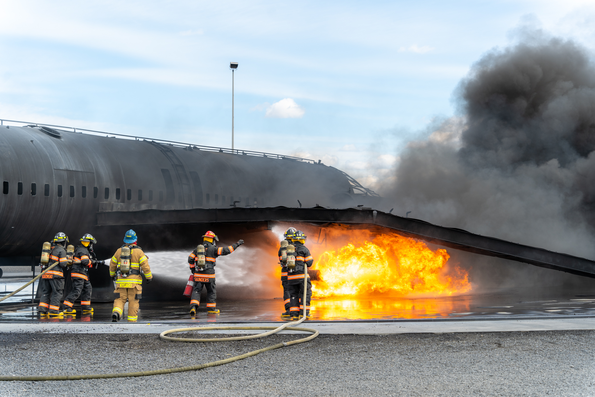 group of firefighters putting out flames on airplane during training