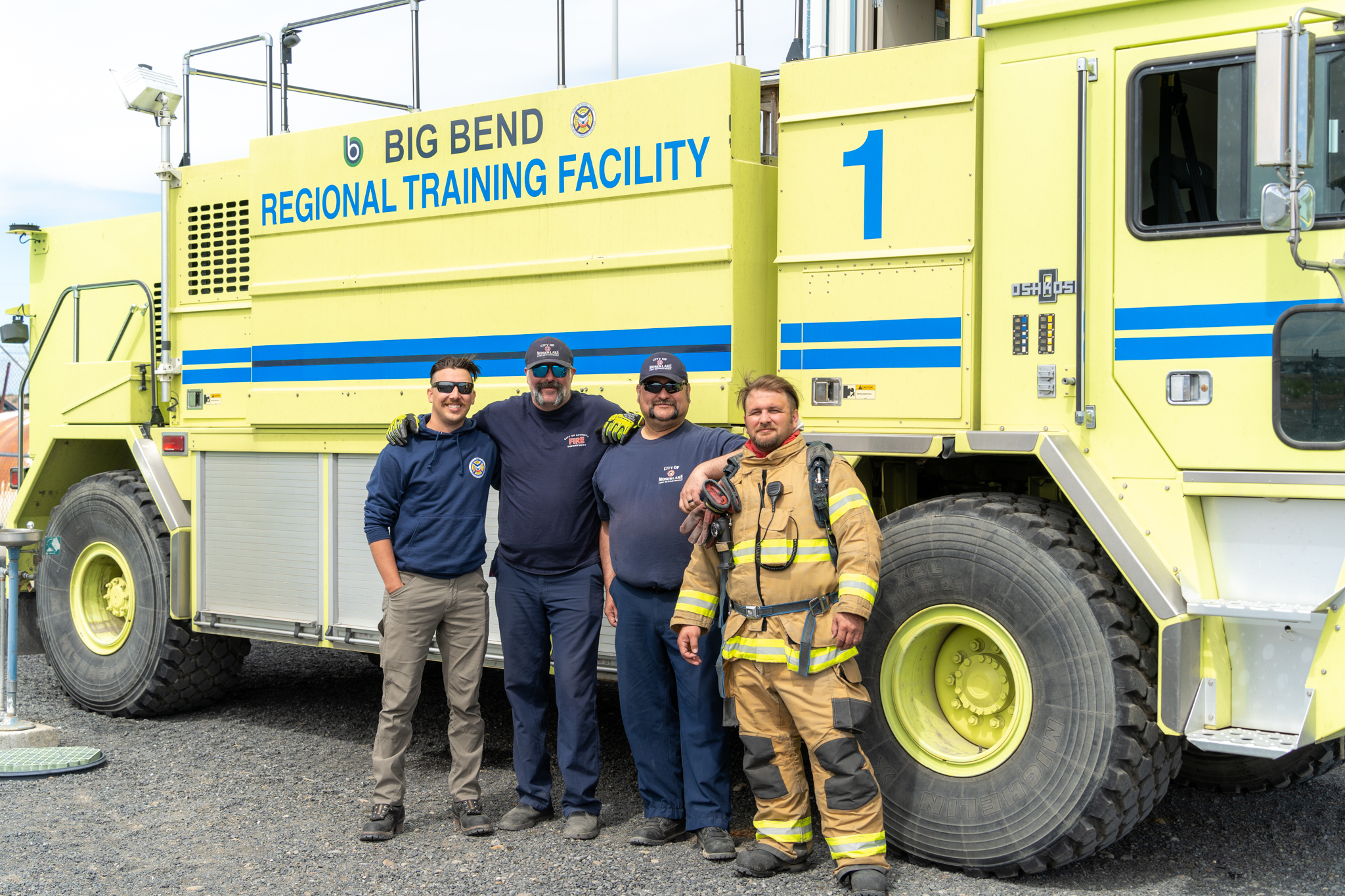 four firefighters in front of yellow fire truck