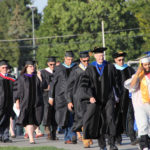 college president and trustees walk onto the field