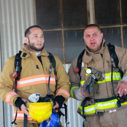 Two firefighters standing by shed