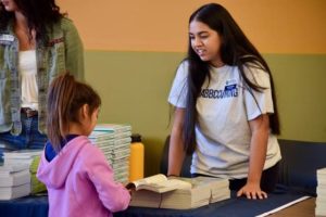 ASB student speaking to a young girl while looking at a book