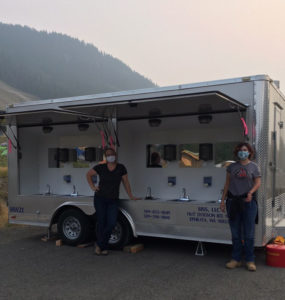 Alumni standing by water truck