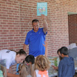 coach handing out books to elementary students