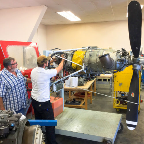 Teacher and student working on airplane motor