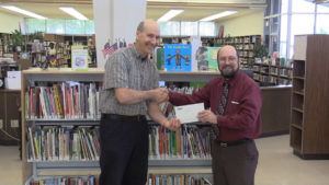 plant manager handing donation to library dean
