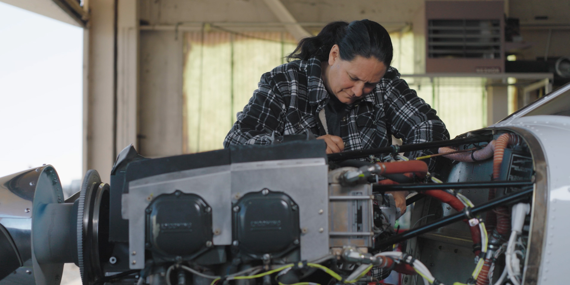 female student working on exposed airplane engine