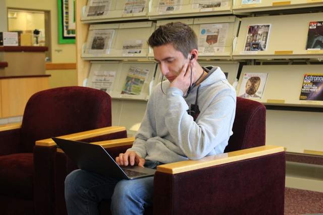 male student in library studying on computer