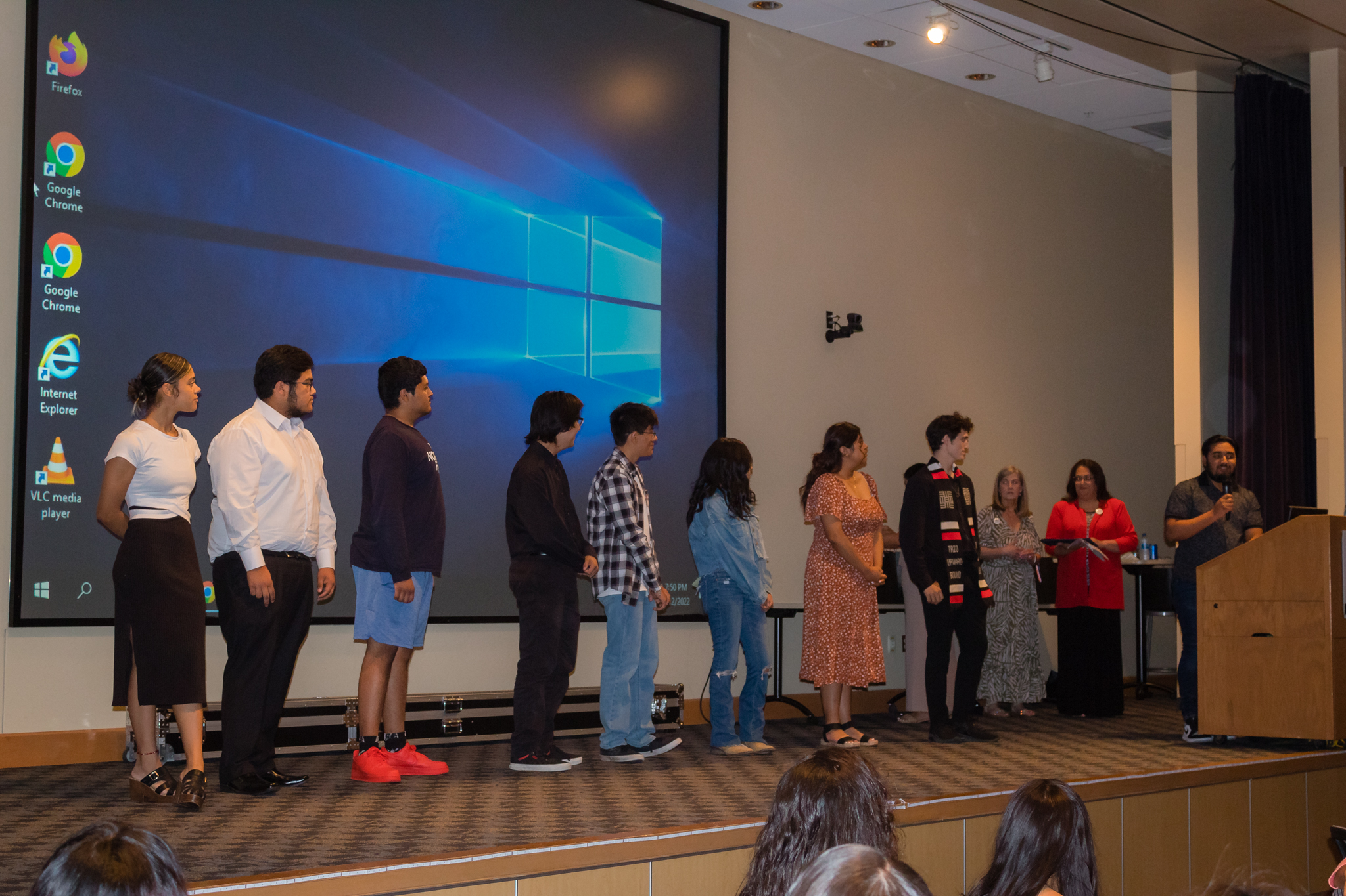 trio staff hand out awards to group of students on stage