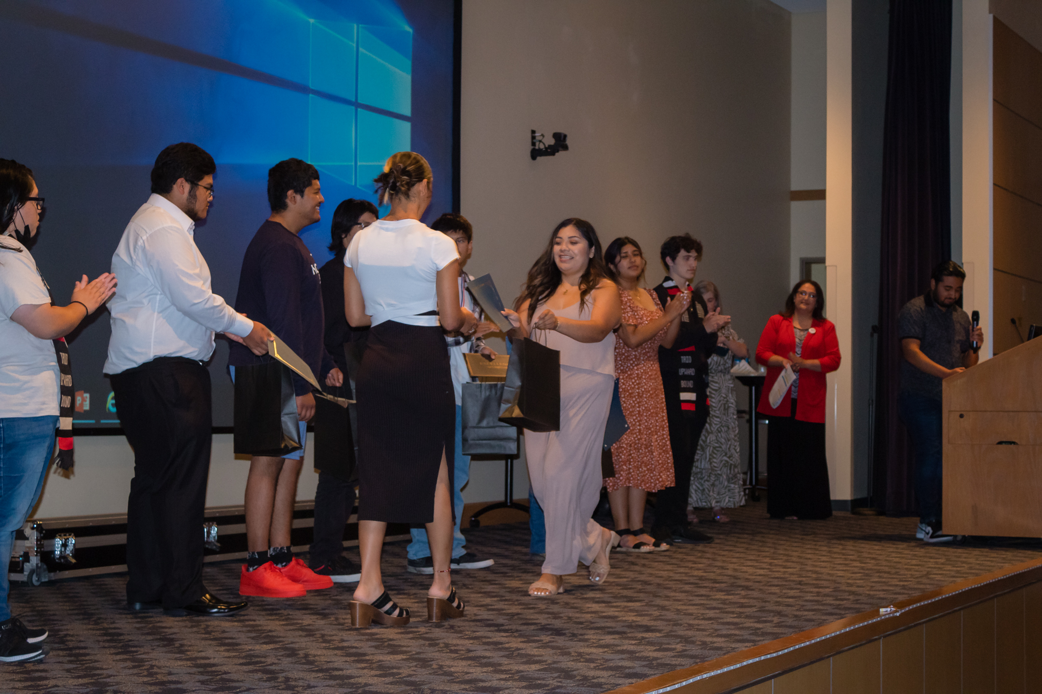 trio staff hand out awards to group of students on stage