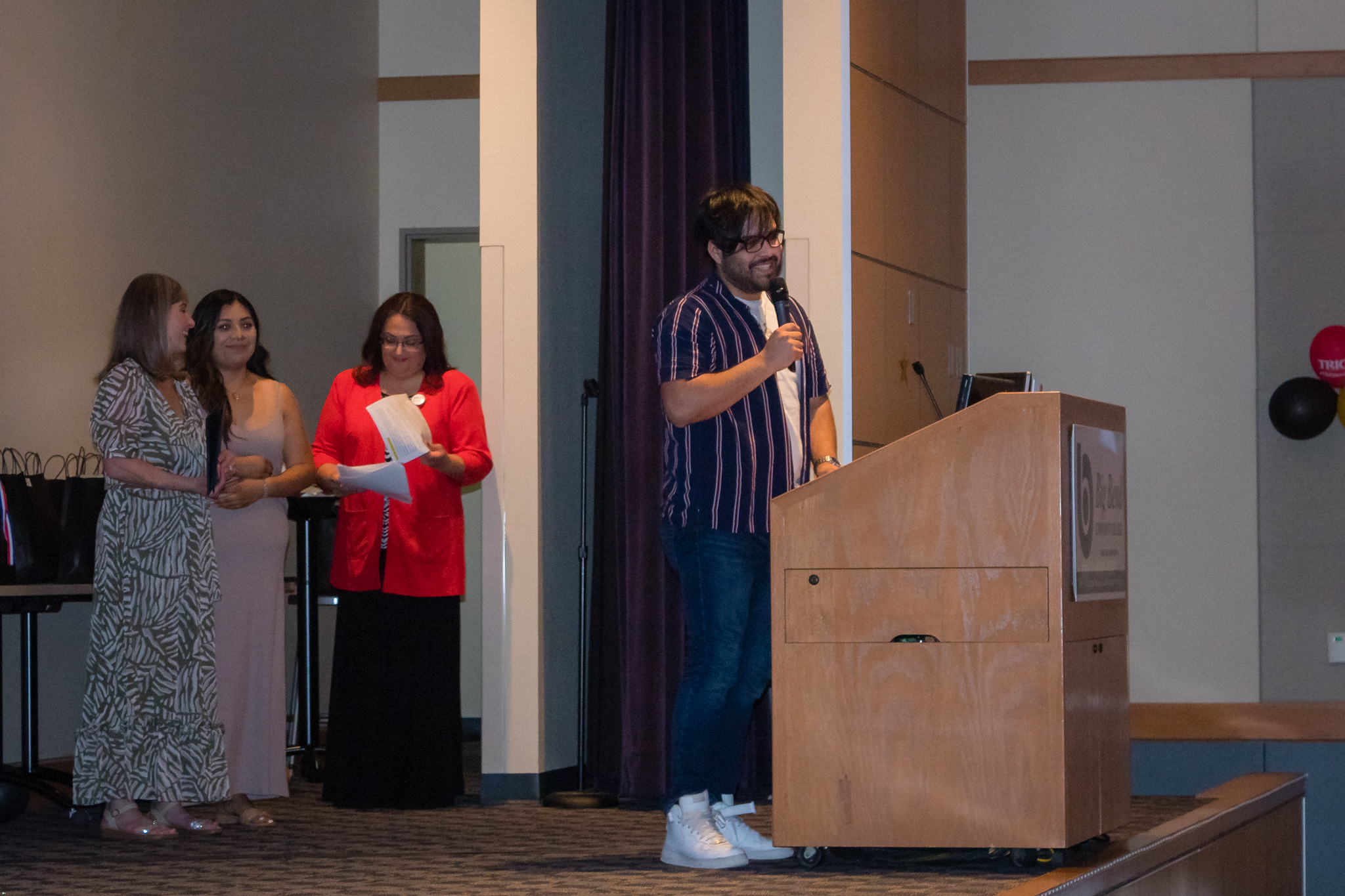 trio staff speaks at podium on stage