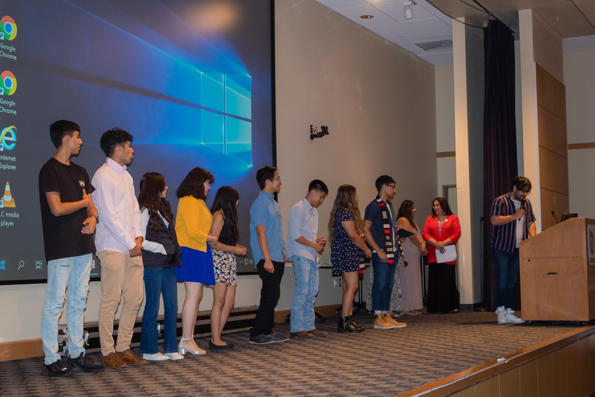 trio staff hand out awards to group of students on stage