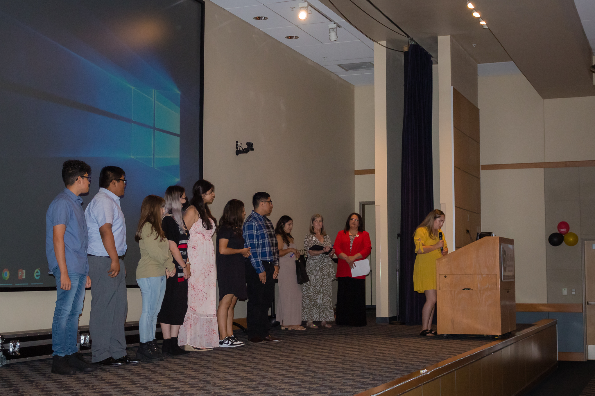 trio staff hand out awards to group of students on stage