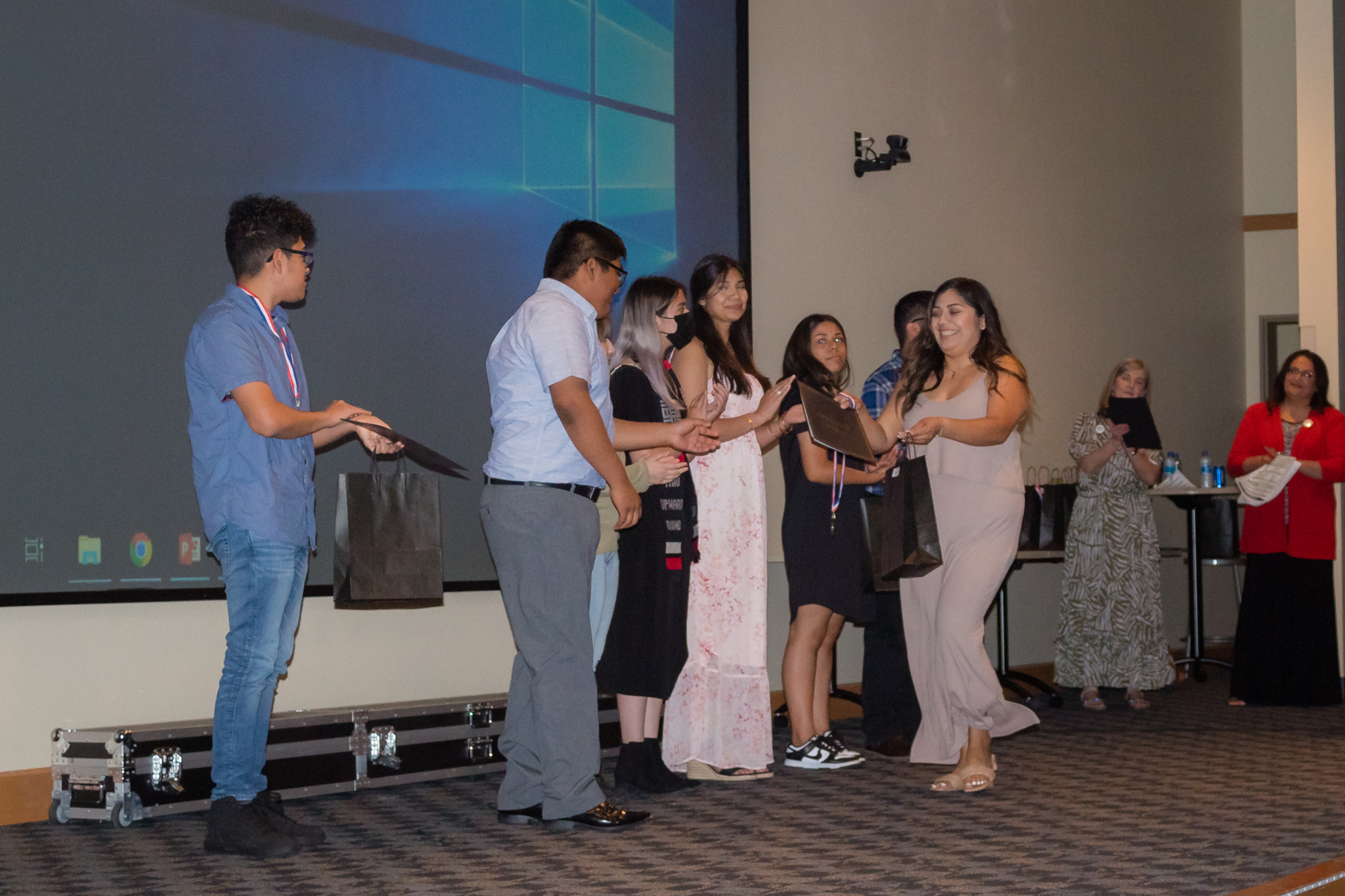 trio staff hand out awards to group of students on stage