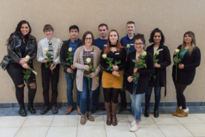 Ten students holding their while roses