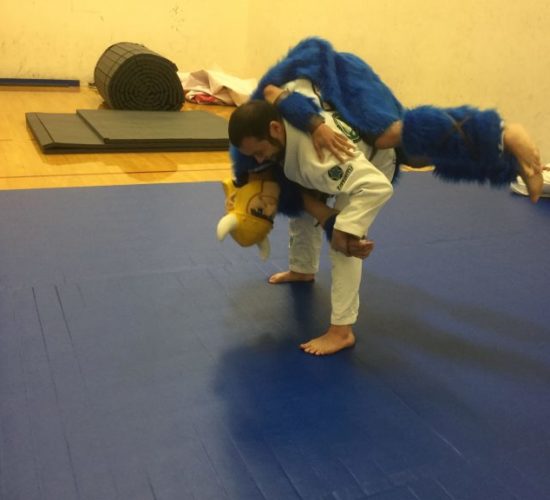 Jiu-Jitsu club member rolling with Viking Mascot on mats