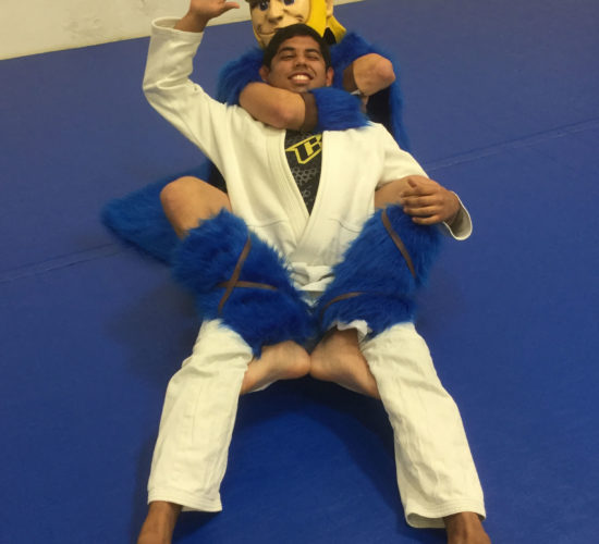 Jiu-Jitsu club member rolling with Viking Mascot on mats