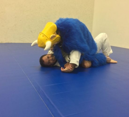 Jiu-Jitsu club member rolling with Viking Mascot on mats