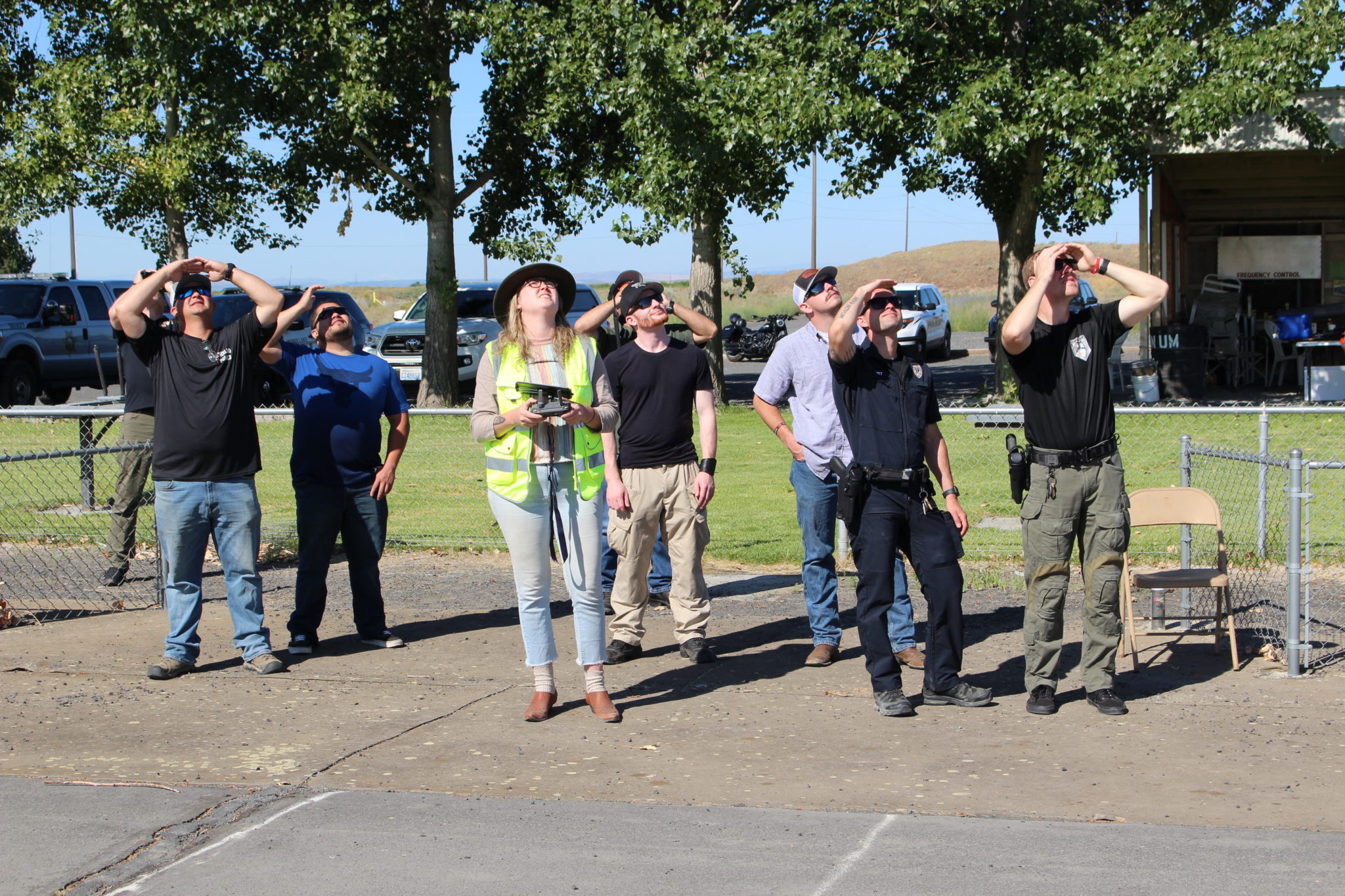 Officer from local law enforcement agencies look up into the sky to try and locate a drone flying at nearly 400 feet.