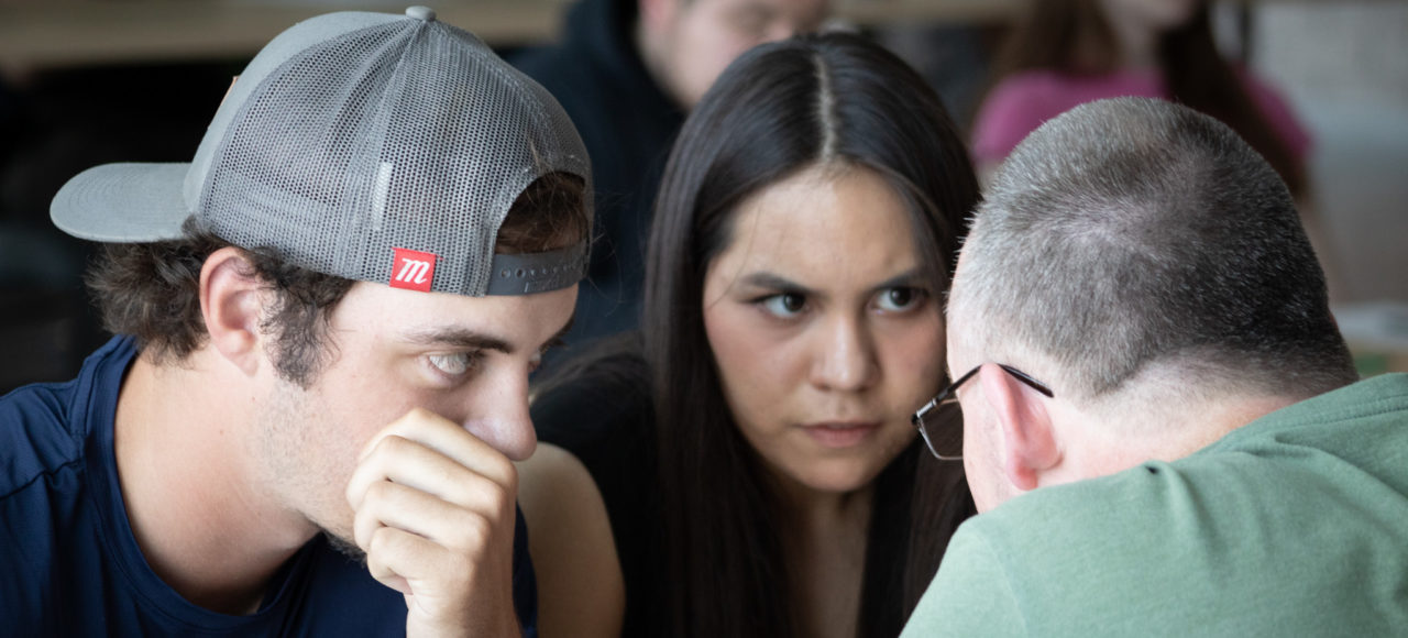 Two students discuss with instructor Chris Riley.