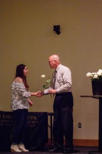 President presenting a flower and shaking hand with student