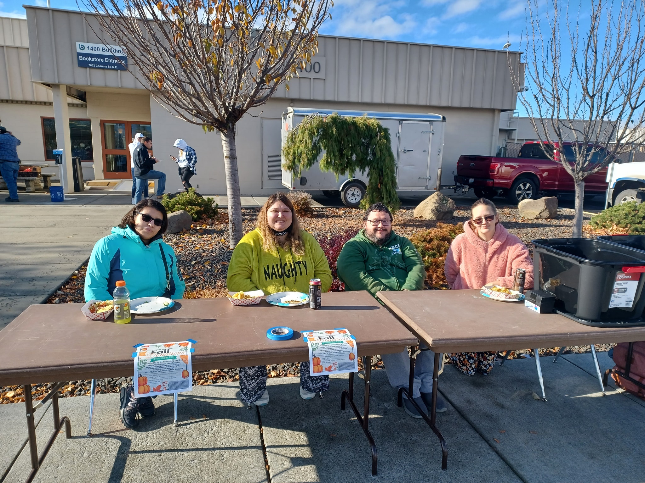 phi theta kappa club members sitting at a table with donation bins