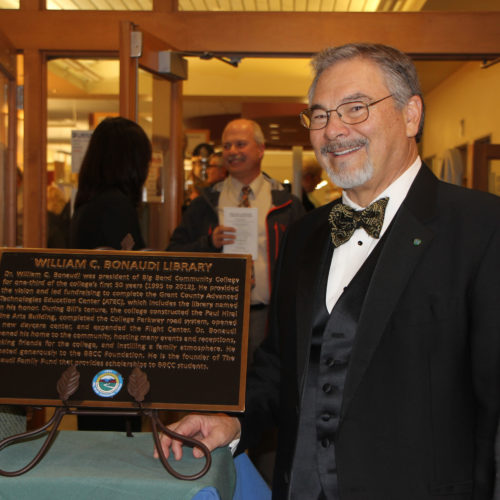 Bill poses with the bronze plaque at the library dedication.