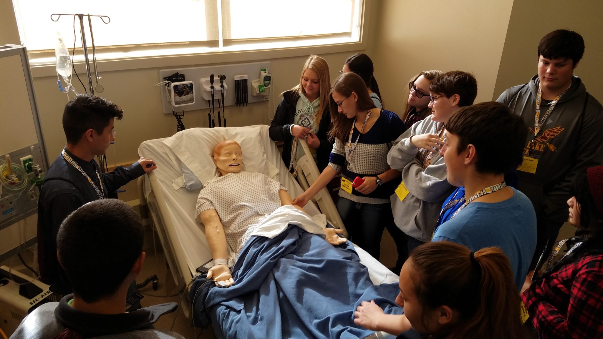 group of 5 students around manikin in sim lab