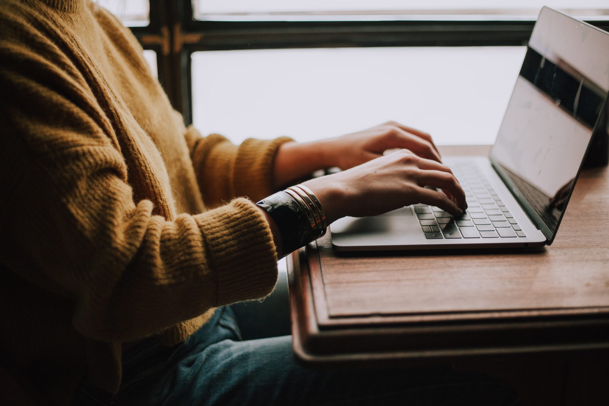 student on laptop, close up of hands typing